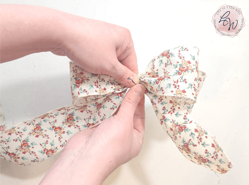 Placing a piece of pipe cleaner around a bow to secure it.