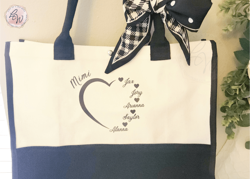 Mother's Day gift tote bag with a DIY design with a heart and "Mimi" at the top left and the names of 5 grandchildren forming the right side of the heart hanging on a hook.