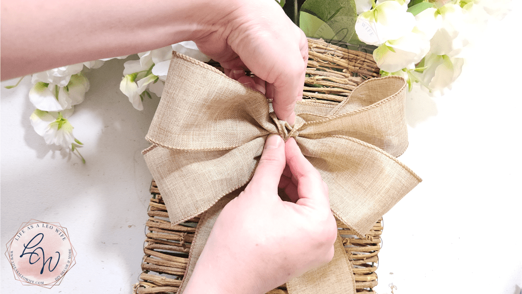 Pressing the bow with hot glue on the back on the center of the floral door basket.
